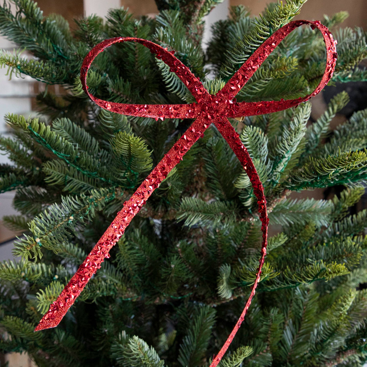 The red Glitter Flakes Bow, clipped to a tree amongst.