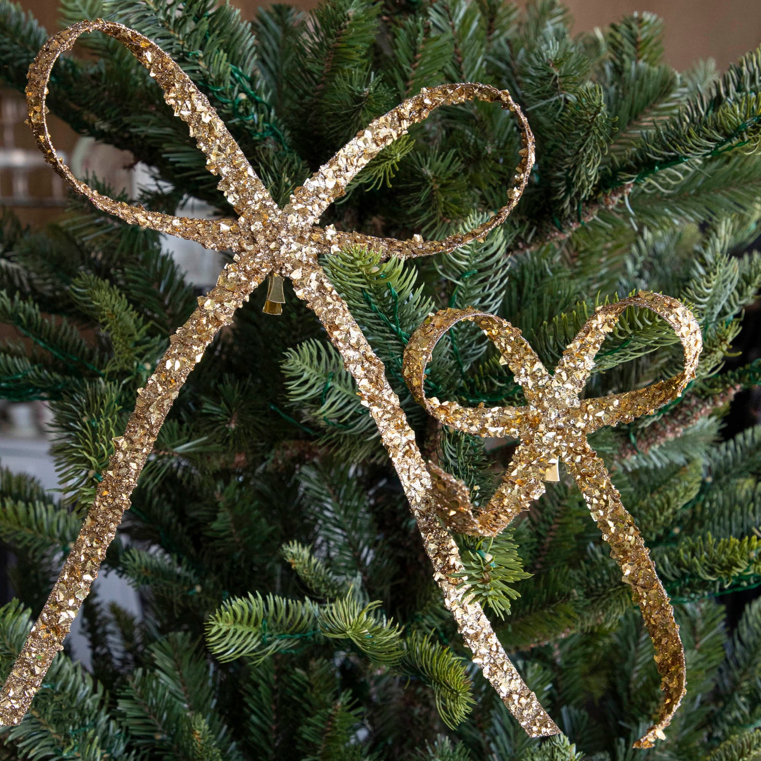  An 8&quot; and 12&quot; gold Glitter Flakes Bow, clipped to a tree.