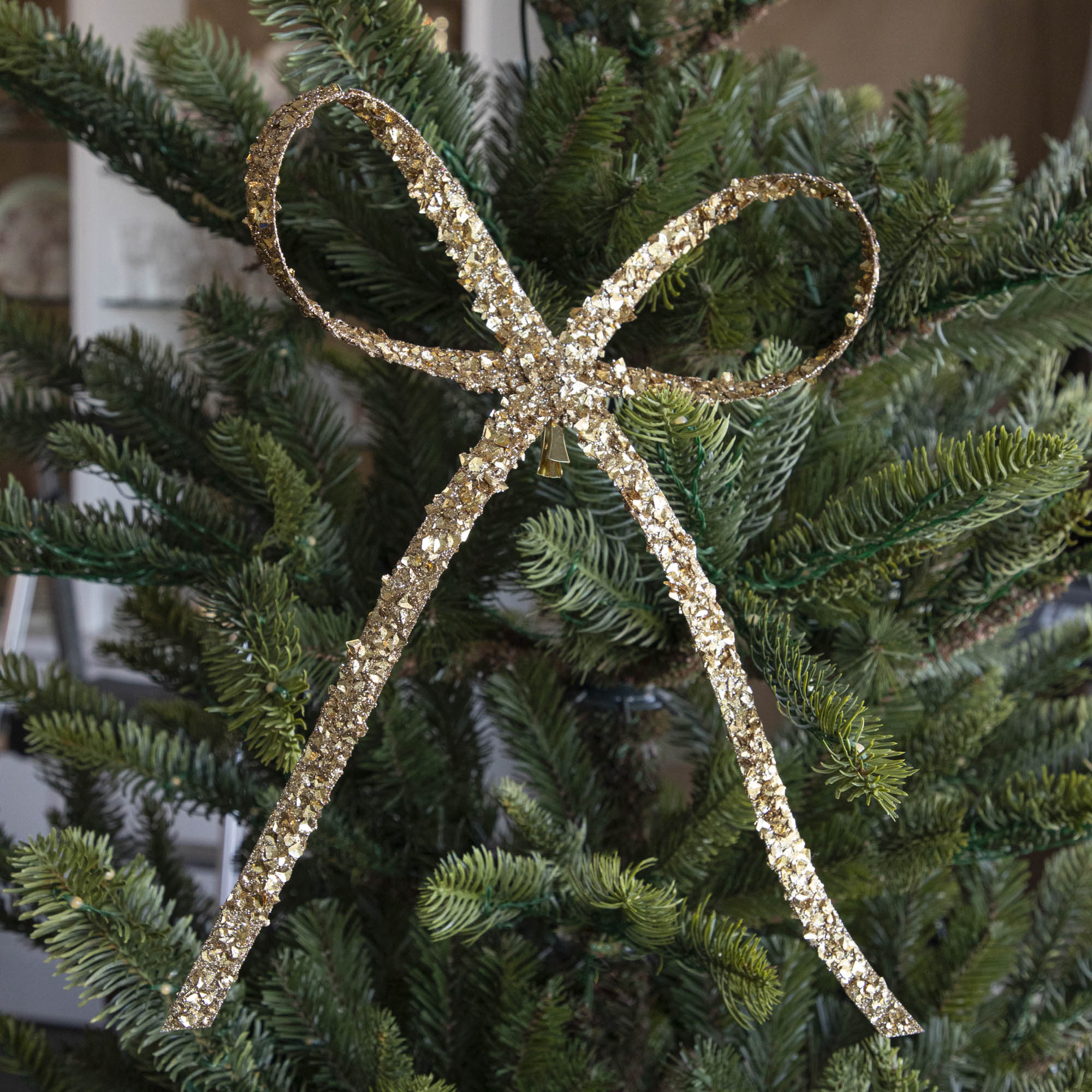 The small, gold Glitter Flakes Bow, clipped to a tree.