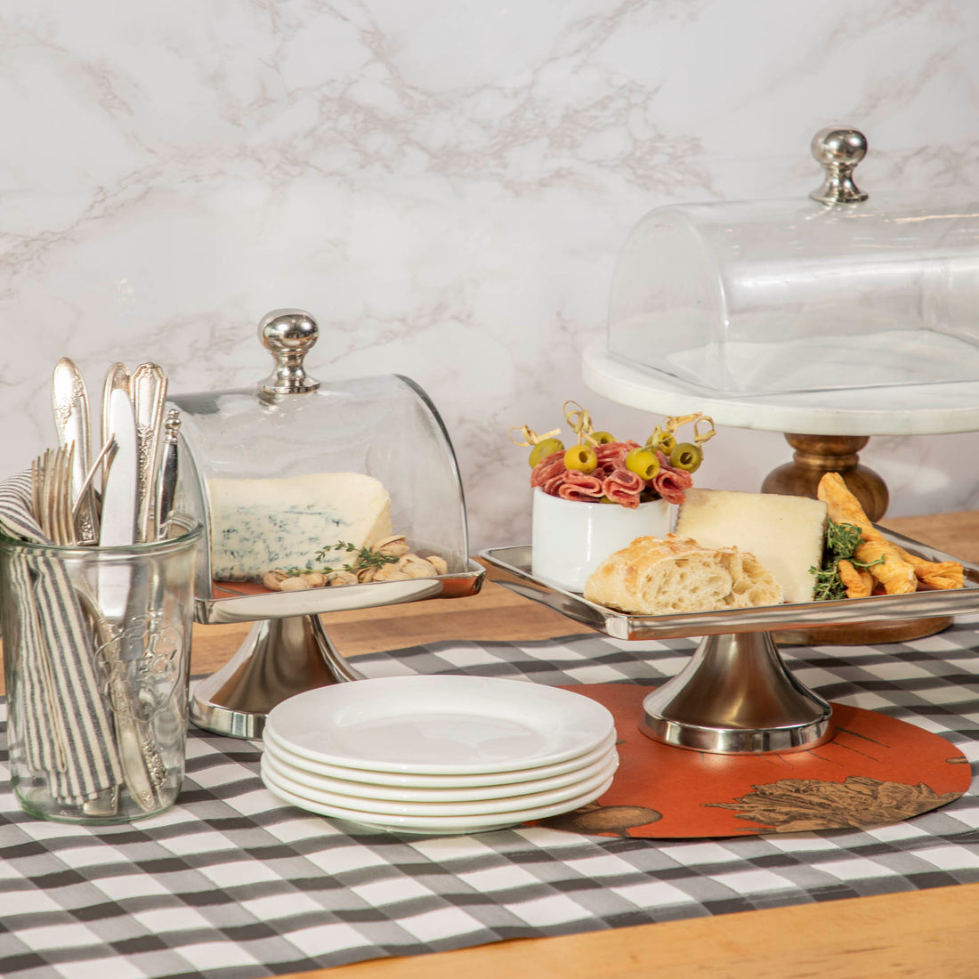 A special Aluminum and Glass Serving Stand &amp; Dome by Hester &amp; Cook is on the glass top table.