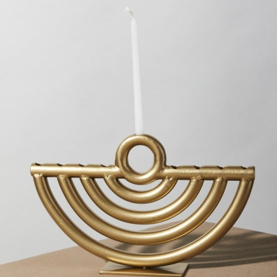 A Golda Menorah with candles on a table.