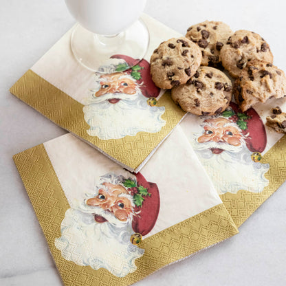 Three Santa Cocktail Napkins under a pile of chocolate chip cookies and a glass of milk.