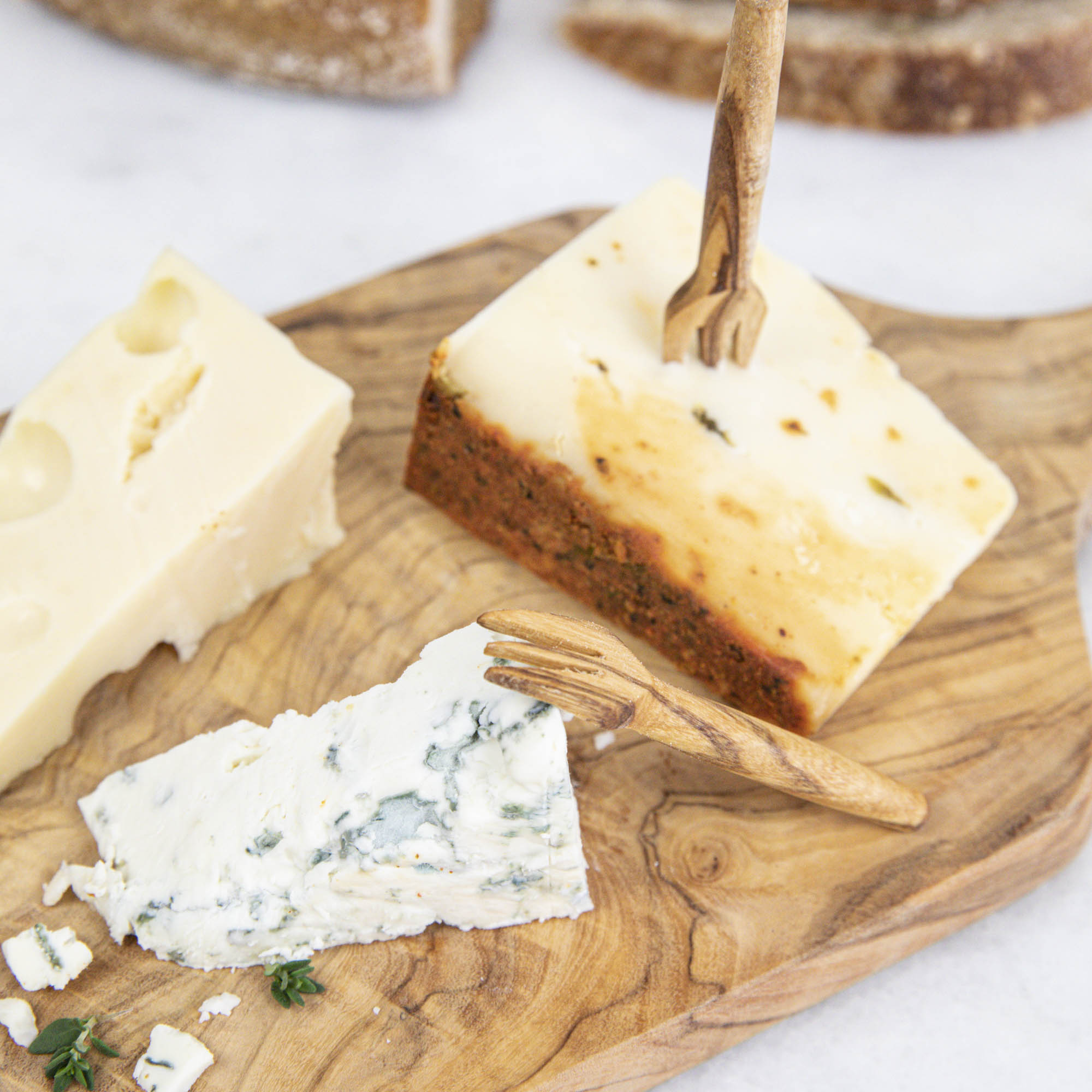 Four pieces of cheese on a Natural Olivewood Cheese Board, ideal for serving hors d&