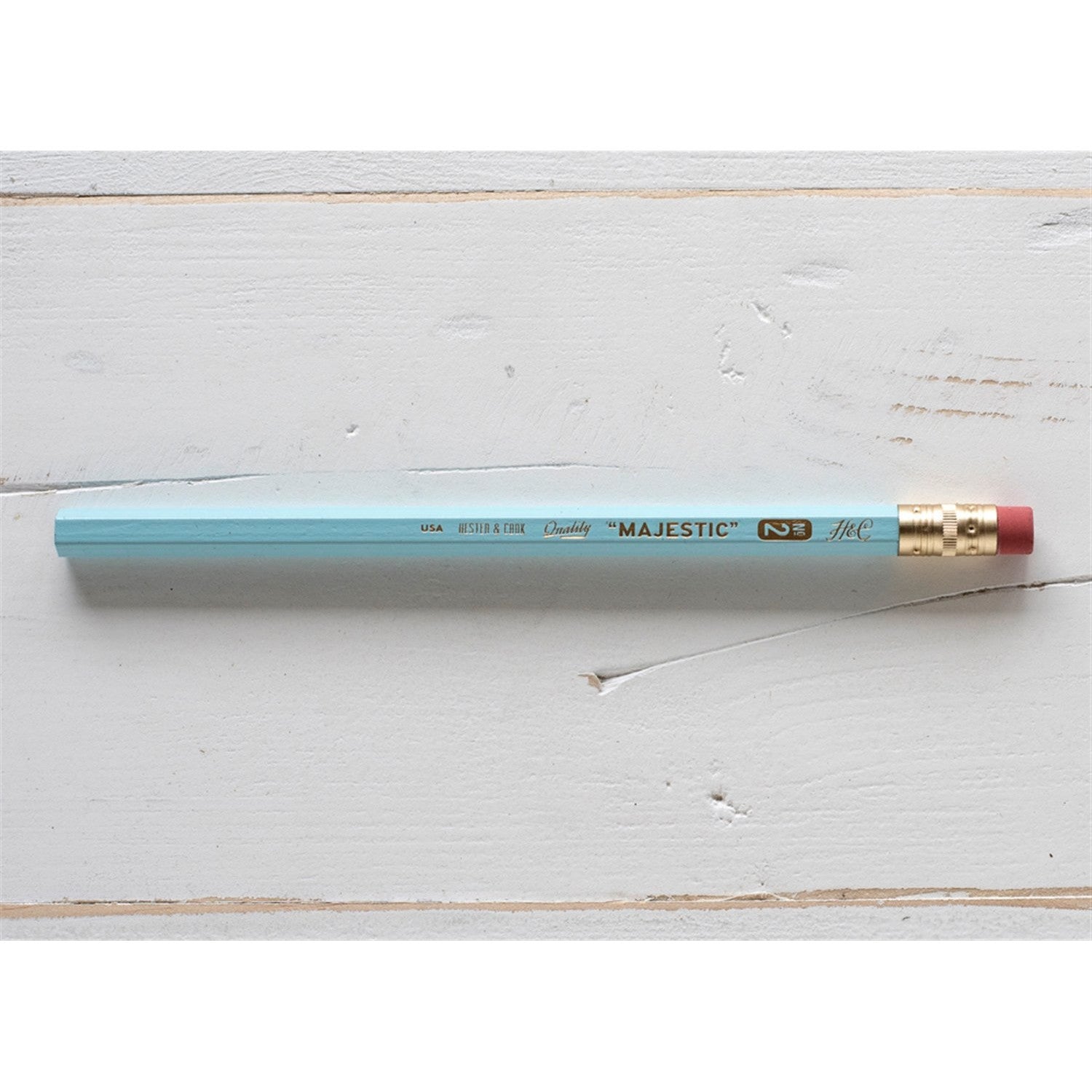 A Hester &amp; Cook jumbo hex pencil with a gold tip on a wooden surface.