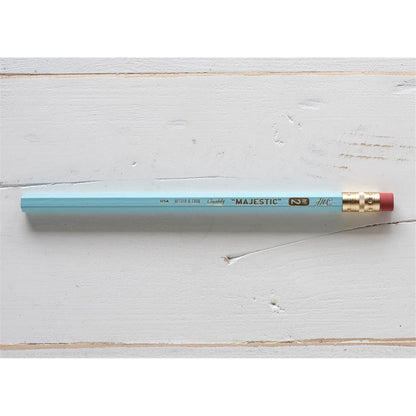A Hester &amp; Cook jumbo hex pencil with a gold tip on a wooden surface.