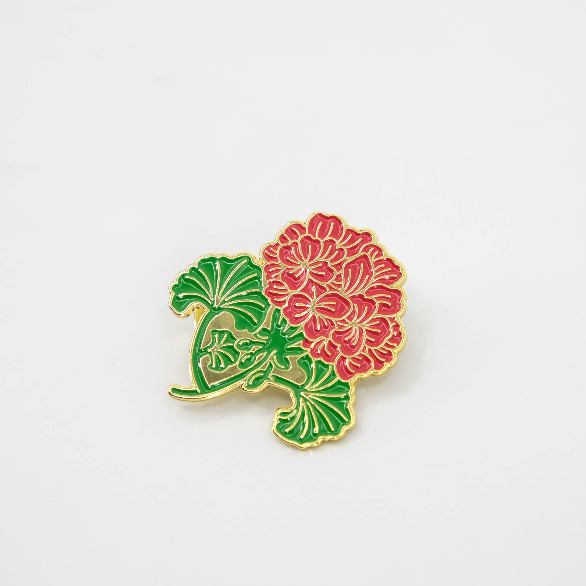 A Hester &amp; Cook Geranium enamel pin with a flower on it.