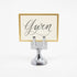 An elegant, chrome, short round stand topped by a flat card-holder with two flat prongs, holding a place card reading "Gwen".