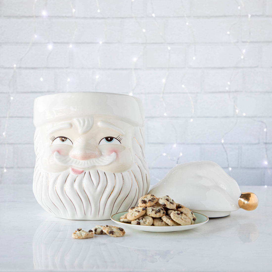 Papa Noel Cookie Jar with the top off and a plate of cookies next to it and string of lights behind